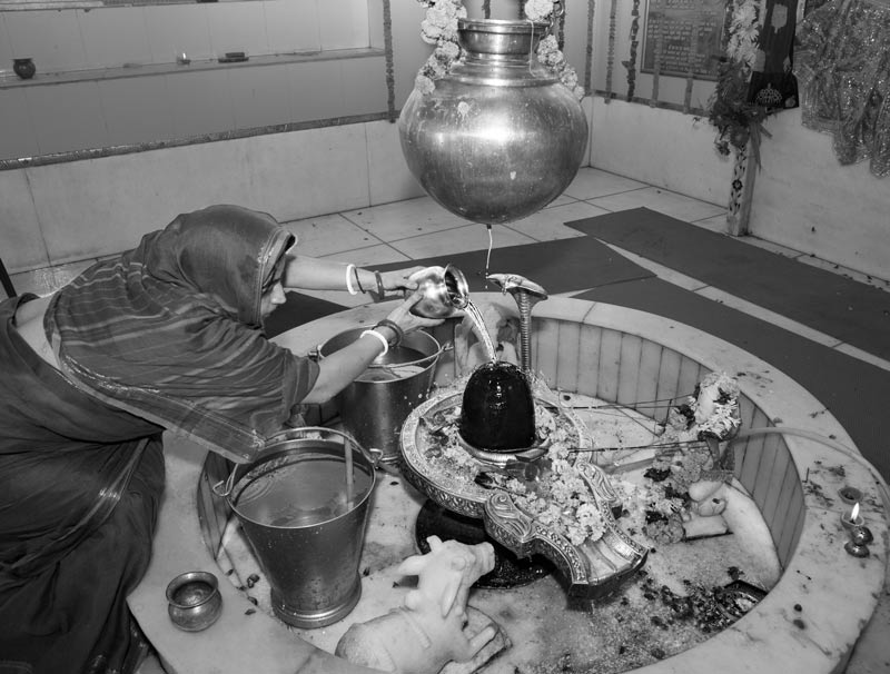 The connection between Water and Religion - A devotee performing 'jalabhisheka' at Shiva Linga in a temple during the holy month of Shravan in South-East district, National Capital Territory of Delhi